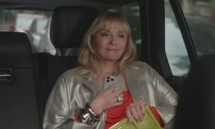 Kim Cattrall clutches a mobile in the back of a taxi