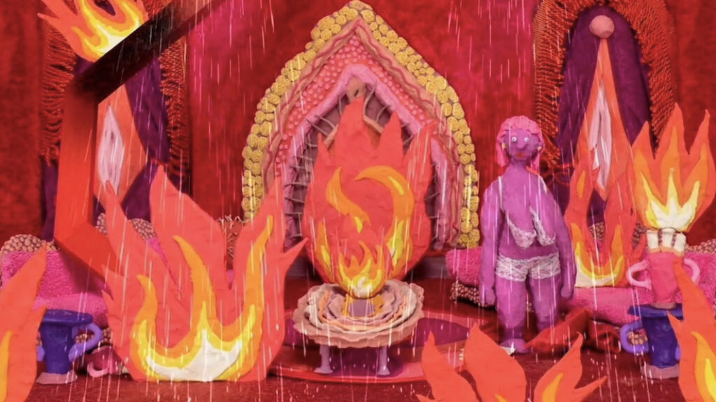 A  clay model scene depicting a womb on fire with woman inside