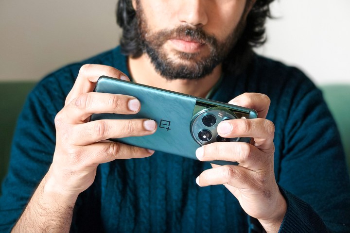 Person holding green OnePlus 12 phone in hands while playing games.