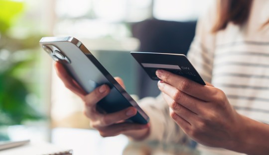 Woman hand holding credit cards and using smartphone for shopping online with payment on internet banking.