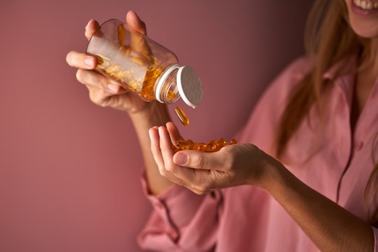 The girl in pink pours omega capsules into her palm.