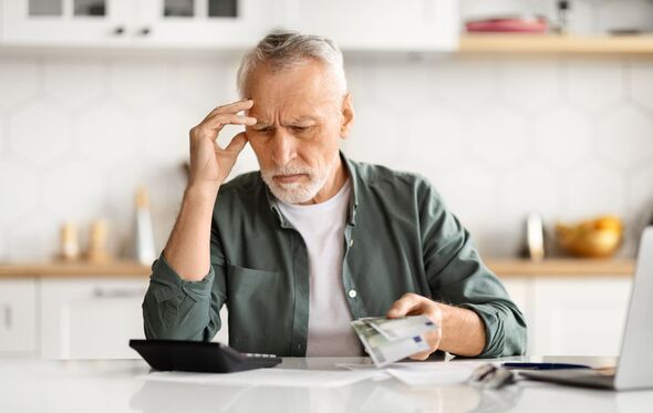 Anxious senior man managing finances, holding cash