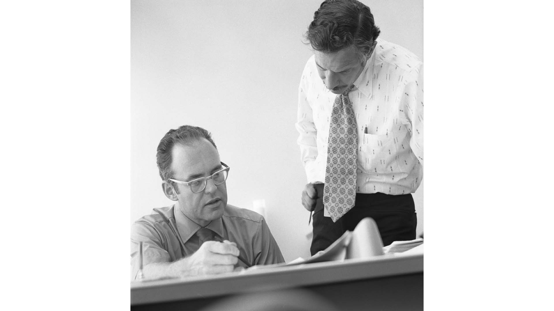 Intel co-founders Gordon Moore and Robert Noyce examining papers on a table