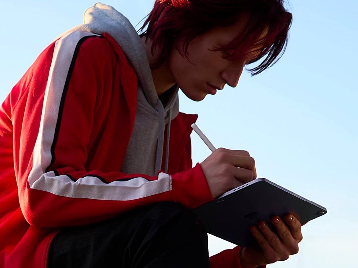 A young woman works on an Apple iPad Air with her Apple Pencil.