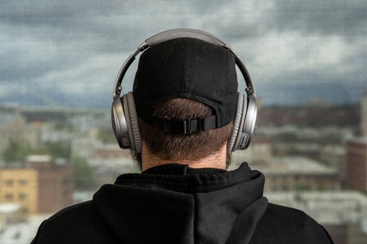 A dude in a baseball hat wearing Bose Quiet Comfort 35 II.