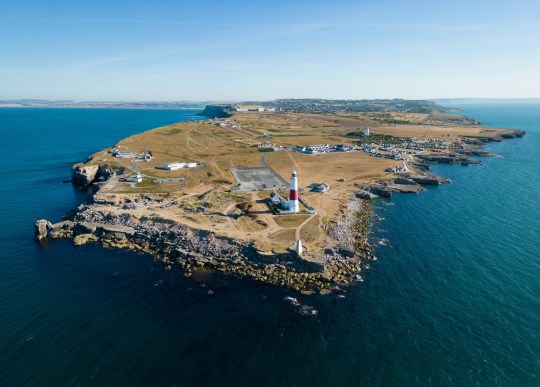 PORTLAND, ENGLAND - AUGUST 08: Morning sun on Portland Bill lighthouse, surrounded by dried out fields, on August 08, 2022 in Portland, United Kingdom. Parts of England and Wales will see temperatures in the high 20s and low 30s celsius, amid record-low rainfall in southern England, prompting several counties to impose hosepipe bans. (Photo by Finnbarr Webster/Getty Images)