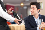 Waiter suggesting a bottle of wine to a customer