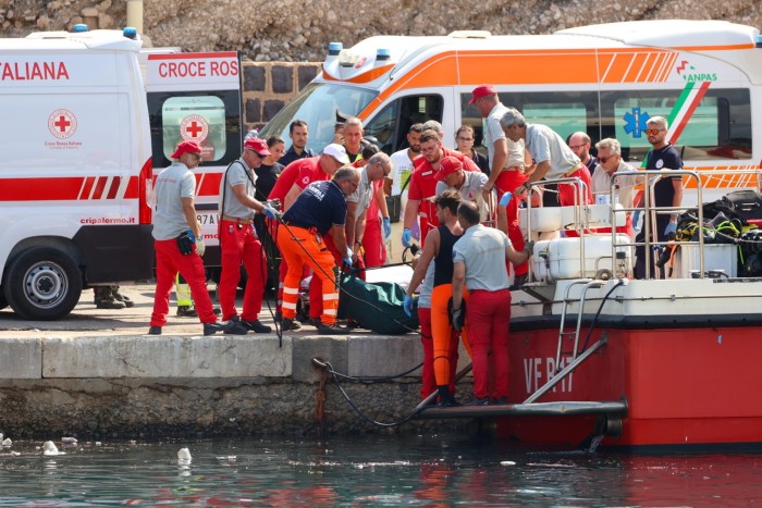 Health workers carry a body bag on the pier as rescue operation continues for the missing people who were on board a sailboat that sank in Palermo