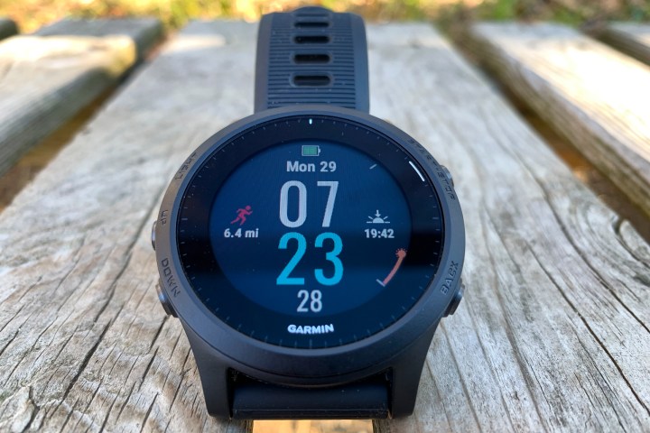 The Garmin Forerunner 945 smartwatch placed on a wooden surface with the display active.