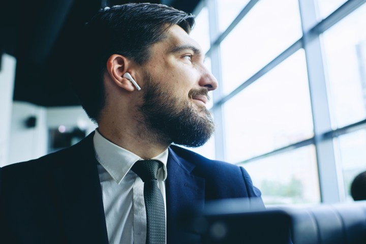 Person listens to audio on truly wireless Bluetooth earbuds similar to Apple AirPods.