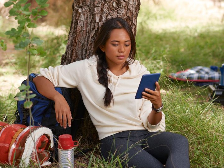 A woman reads on a standard Amazon Kindle.