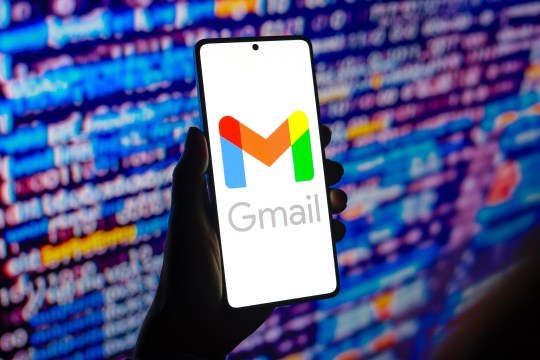 A hand holding a mobile phone with a Gmail graphic on it