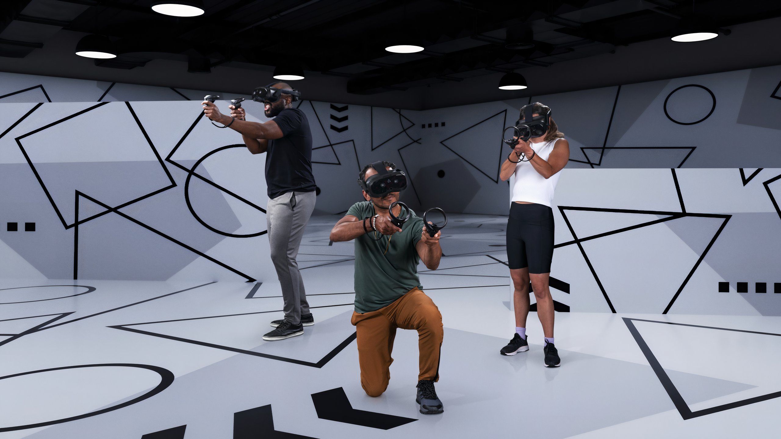 Three people wearing Vive Focus Vision headsets and holding controllers like they're playing laser tag.