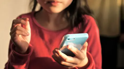 Getty Images A stock image of a young child holding a pale blue smartphone