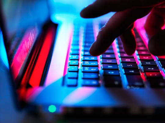 Man typing at his laptop computer at night.