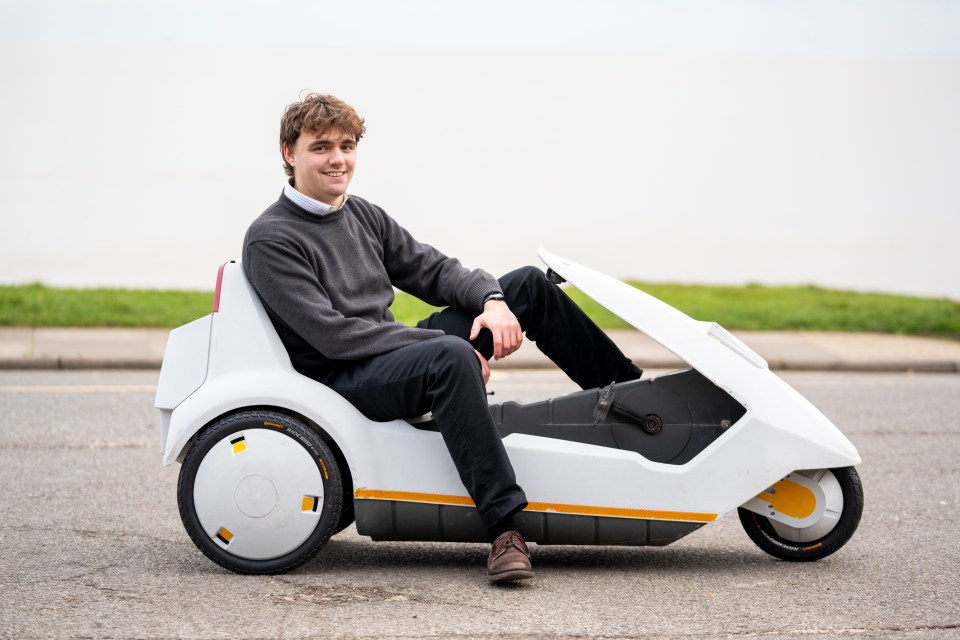 Man sitting in a Sinclair C5 electric vehicle.