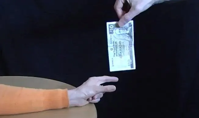 Hand passing a banknote between two people.