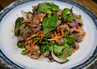 Laap Pèt: Viande de canard émincée accompagnée de menthe, de coriandre, de jeunes oignons et saupoudrée de riz gluant grillé pilé.