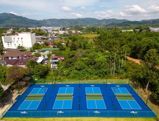 Aerial view of multiple pickleball courts at Pickleball Phuket, surrounded by lush greenery and urban infrastructure in Phuket, Thailand.