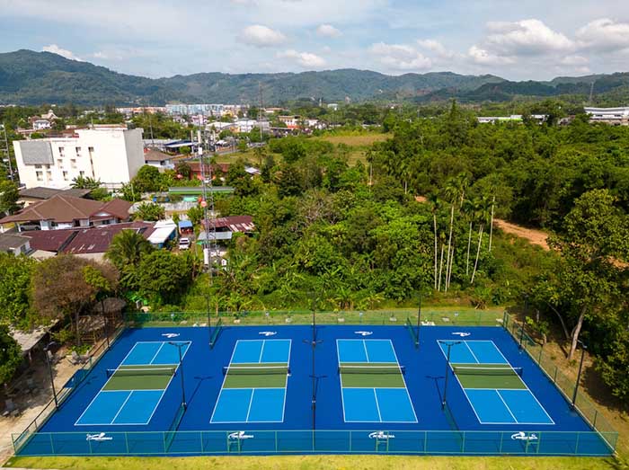 Aerial view of multiple pickleball courts at Pickleball Phuket, surrounded by lush greenery and urban infrastructure in Phuket, Thailand.