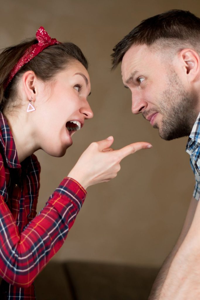 Woman pointing finger at man while he stares at her with an annoyed look