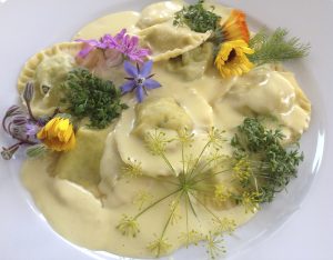 Mit cremiger "Sahne"-Soße und Blumendeko schmecken die veganen Teigtaschen besonder gut