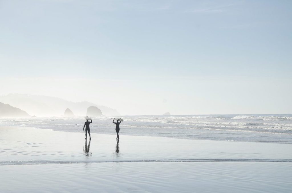 Surfers walking on a beach, carrying surfboards