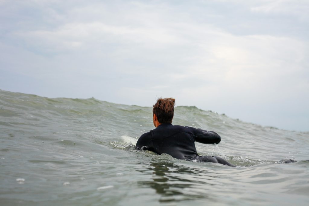 Surfer paddling in the ocean towards wave