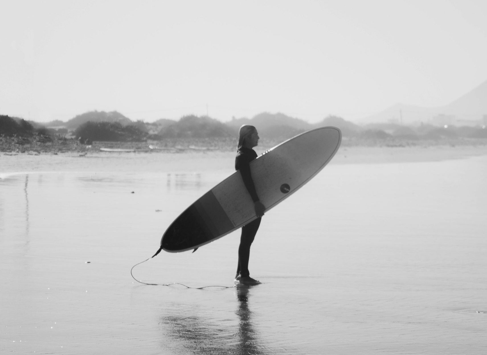 Black and white picture of surfer holding a surfboard