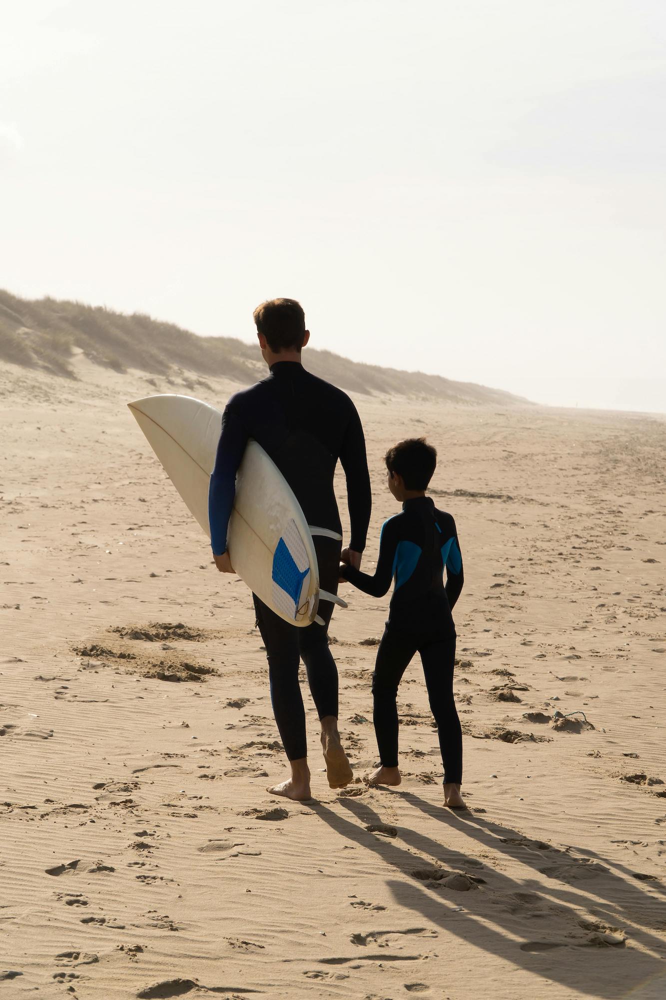 Surfer dad and son walking on the beach