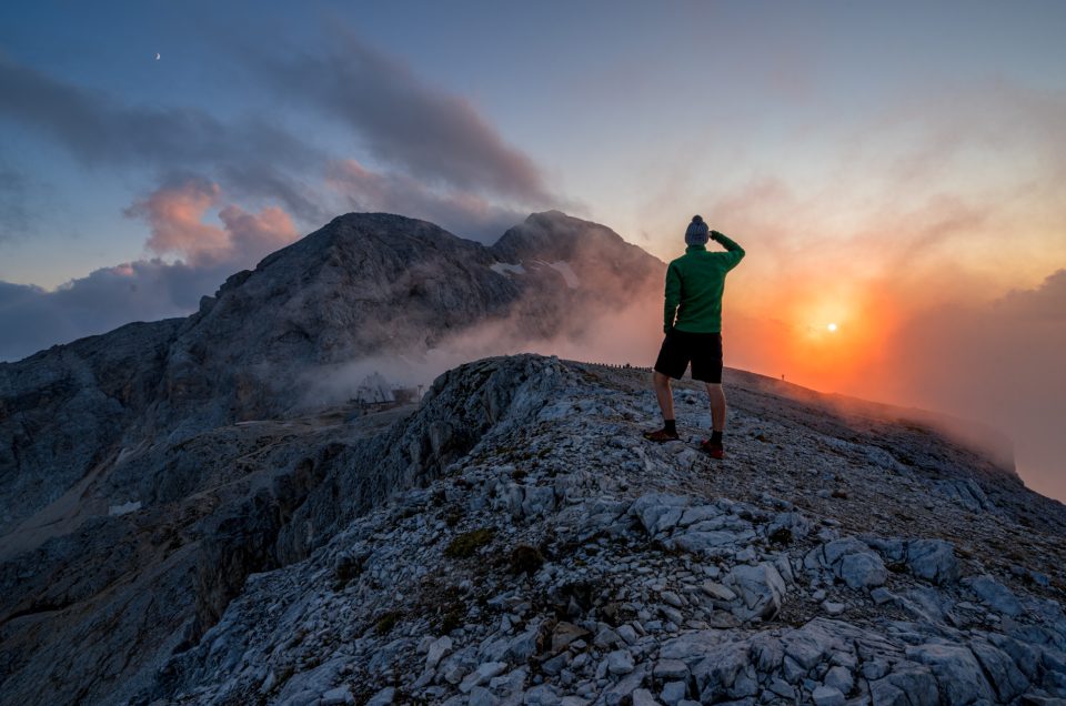 Hiker enjoys view at sunset and mountain Triglav