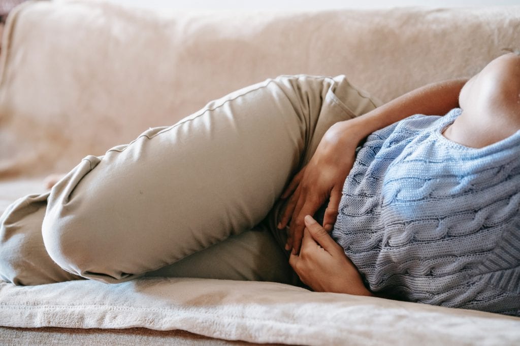 woman holds stomach in pain