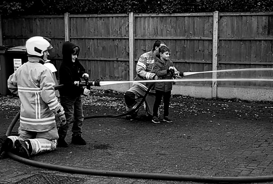 Kids with fire fighters using hoses