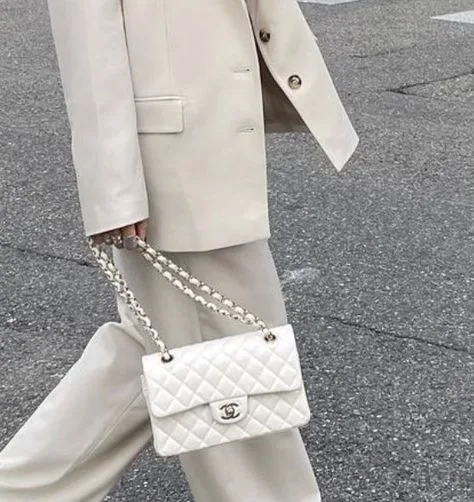 Woman in a white beige outfit wearing a white chanel double flap bag
