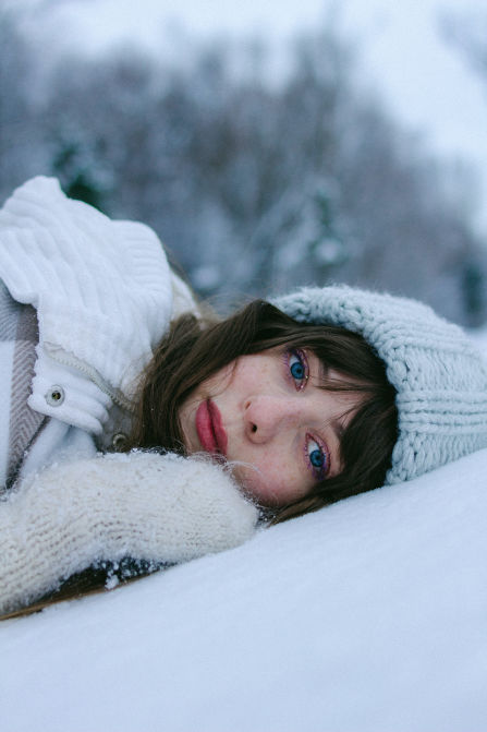 Woman winter skincare routine laying in the snow with her face