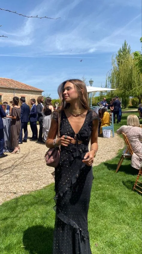 Woman standing at a garden party wearing a long and elegant black dress