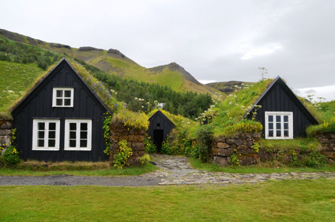 Blue farmhouse summerhouse covering in green grass