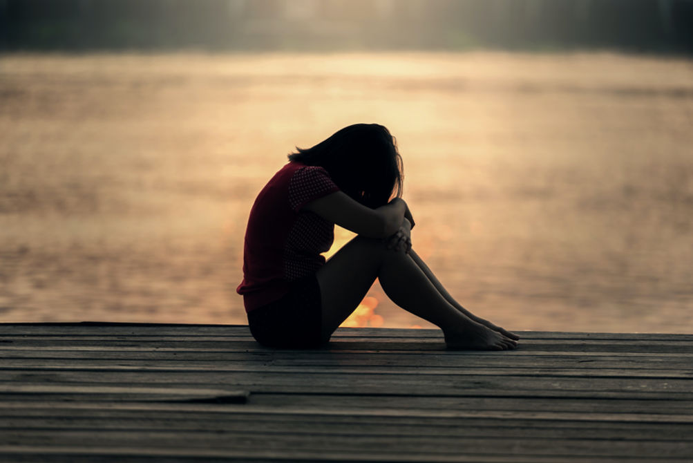 Woman sitting by the water grieving breakup stage