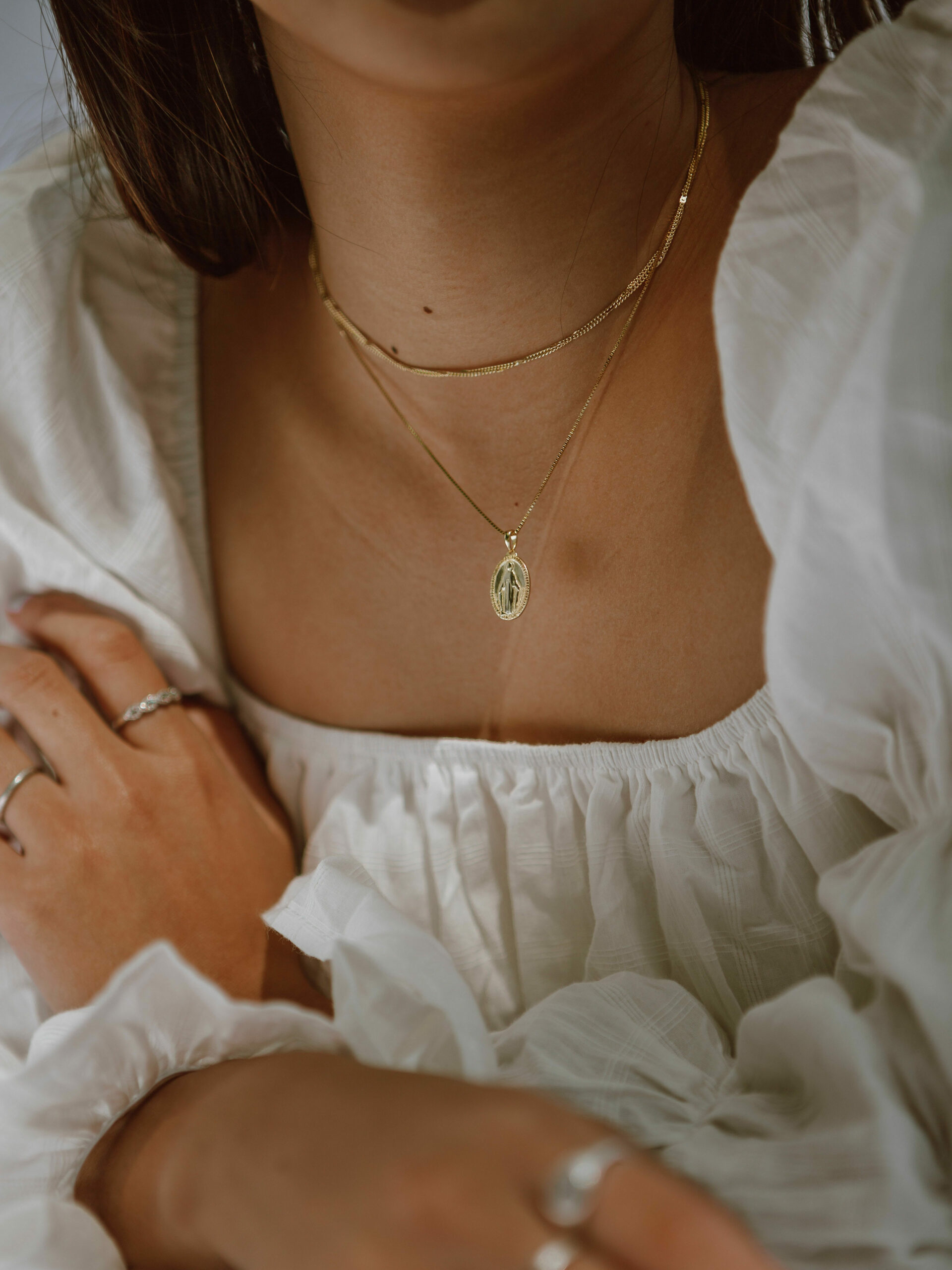 Woman wearing a white top and jewellery in a quiet luxury and elegant fashion style