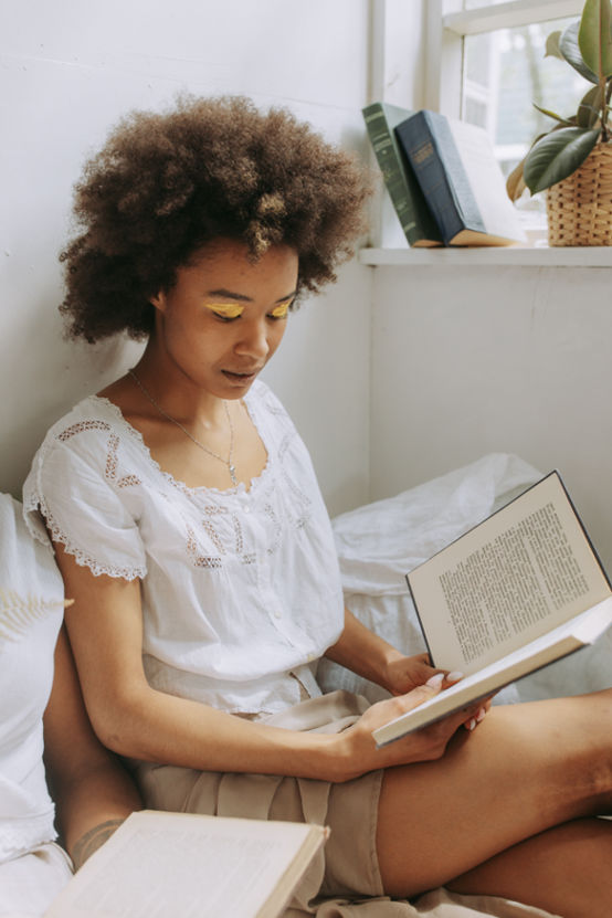 Woman sitting in her bed reading a book