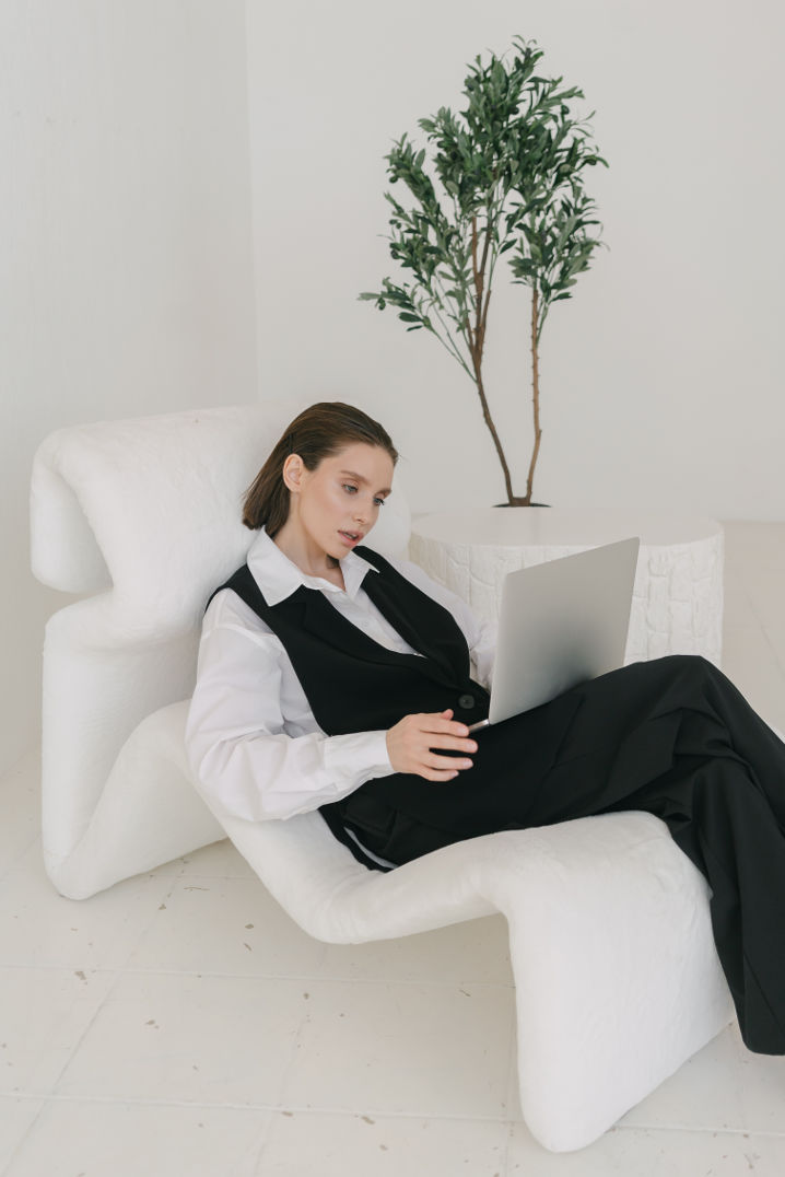 Woman sitting in a lounge chair in a job outfit suit with a computer