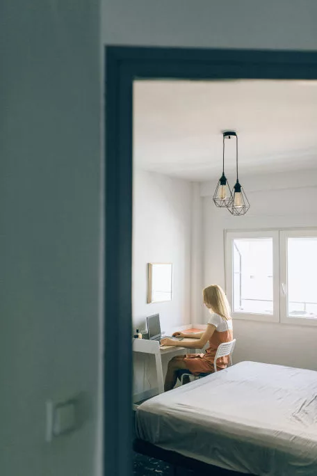 Woman sitting in her room working at a small desk in bedroom