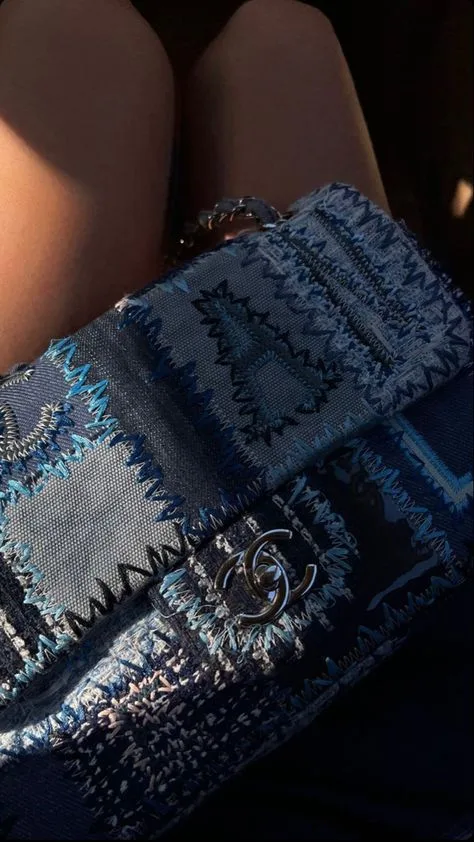 A blue cowboy chanel bag laying on the legs of a woman