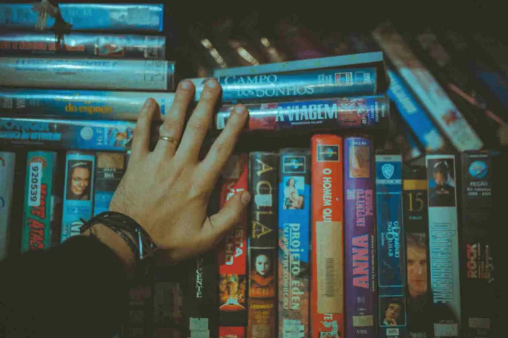 A man's hand touching a group of movies showcasing books made into movies.