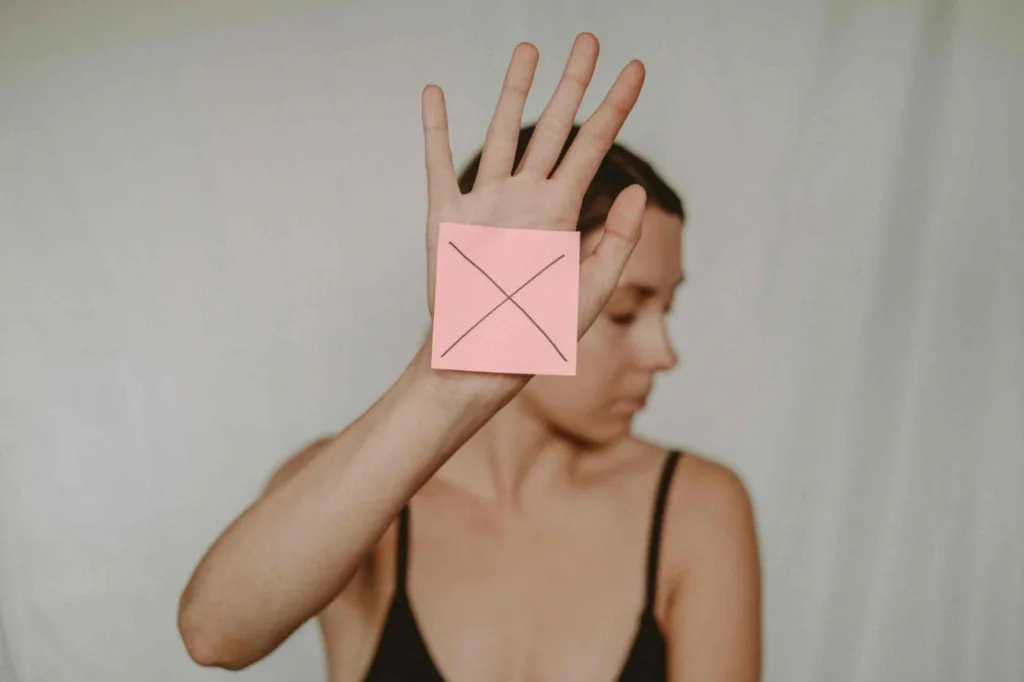 Picture of a woman with an X sign in her hand showcasing rejection.