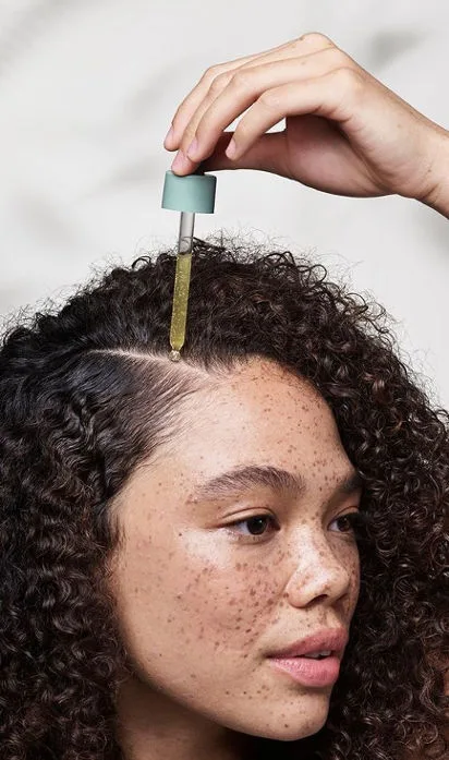woman applying hair oil to scalp