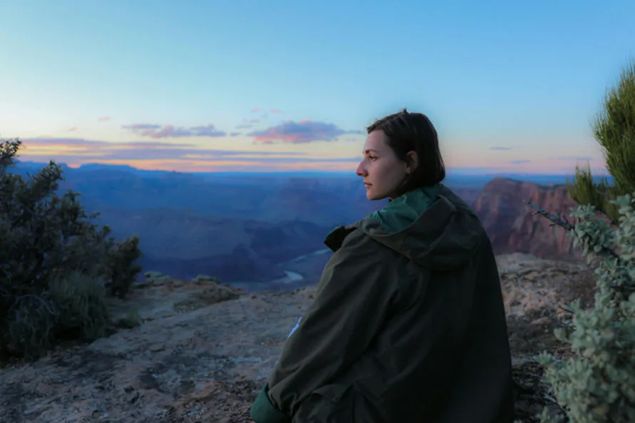 Woman sitting on mountain looking over the horizon enjoying the views and manifesting life