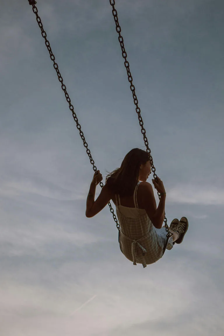 Girl on a swing looking over the sky manifesting life