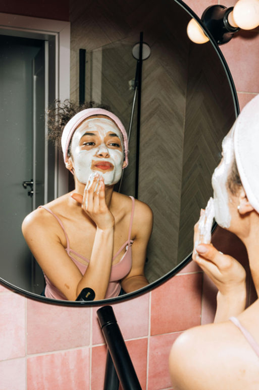 woman doing a face mask in front of the mirror