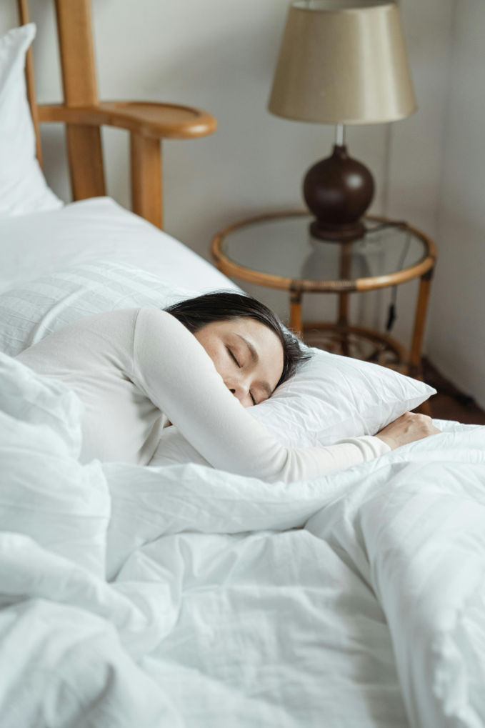 mulher dormindo em uma cama com cobertores brancos